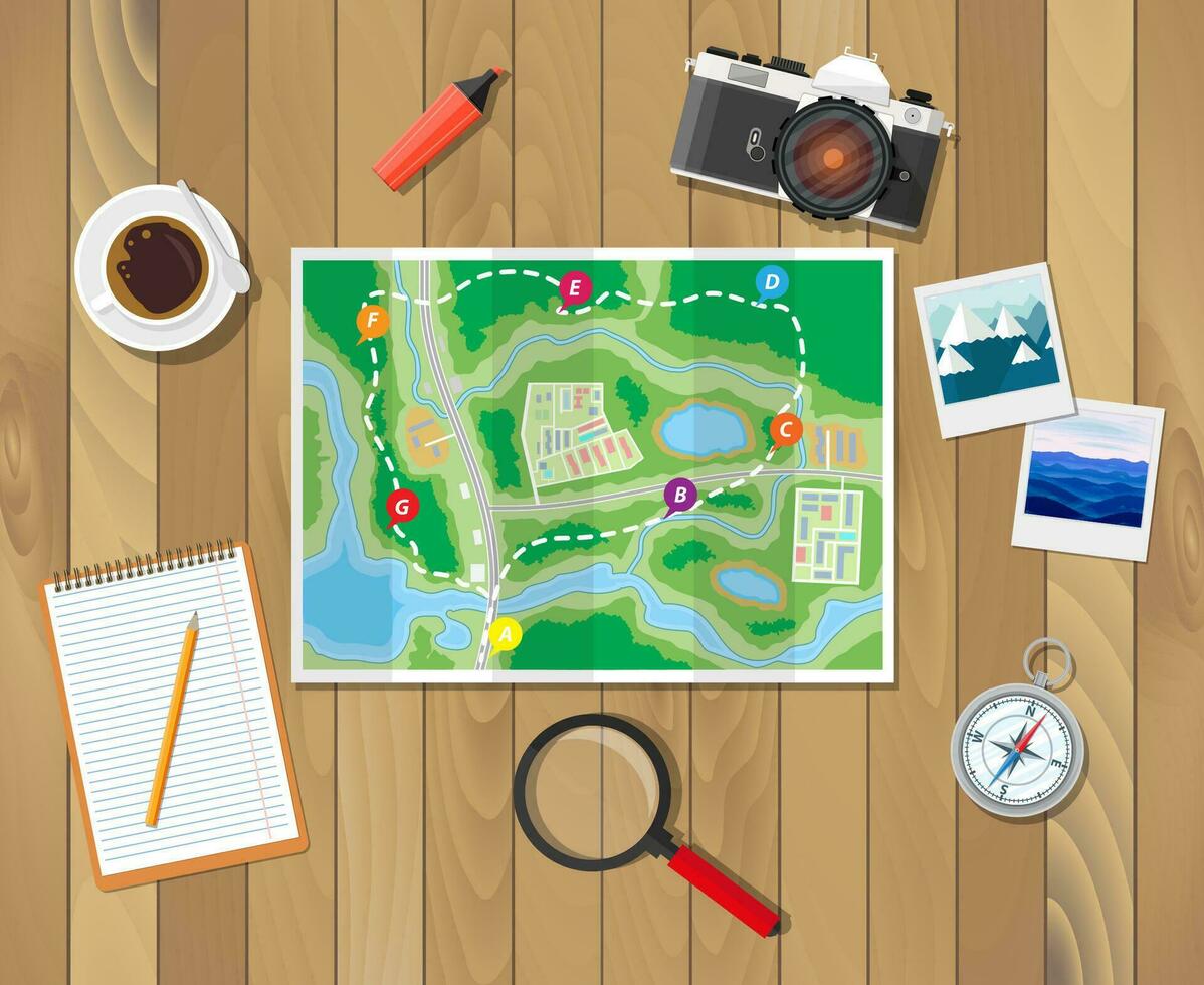 A paper map, notebook and bicycle bell laid out on a wooden table during route planning